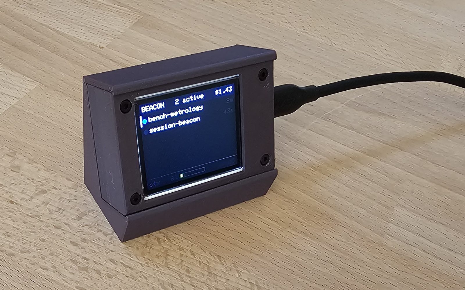 The assembled beacon on a wooden desk seen from an angle, USB-C cable attached, showing two sessions.