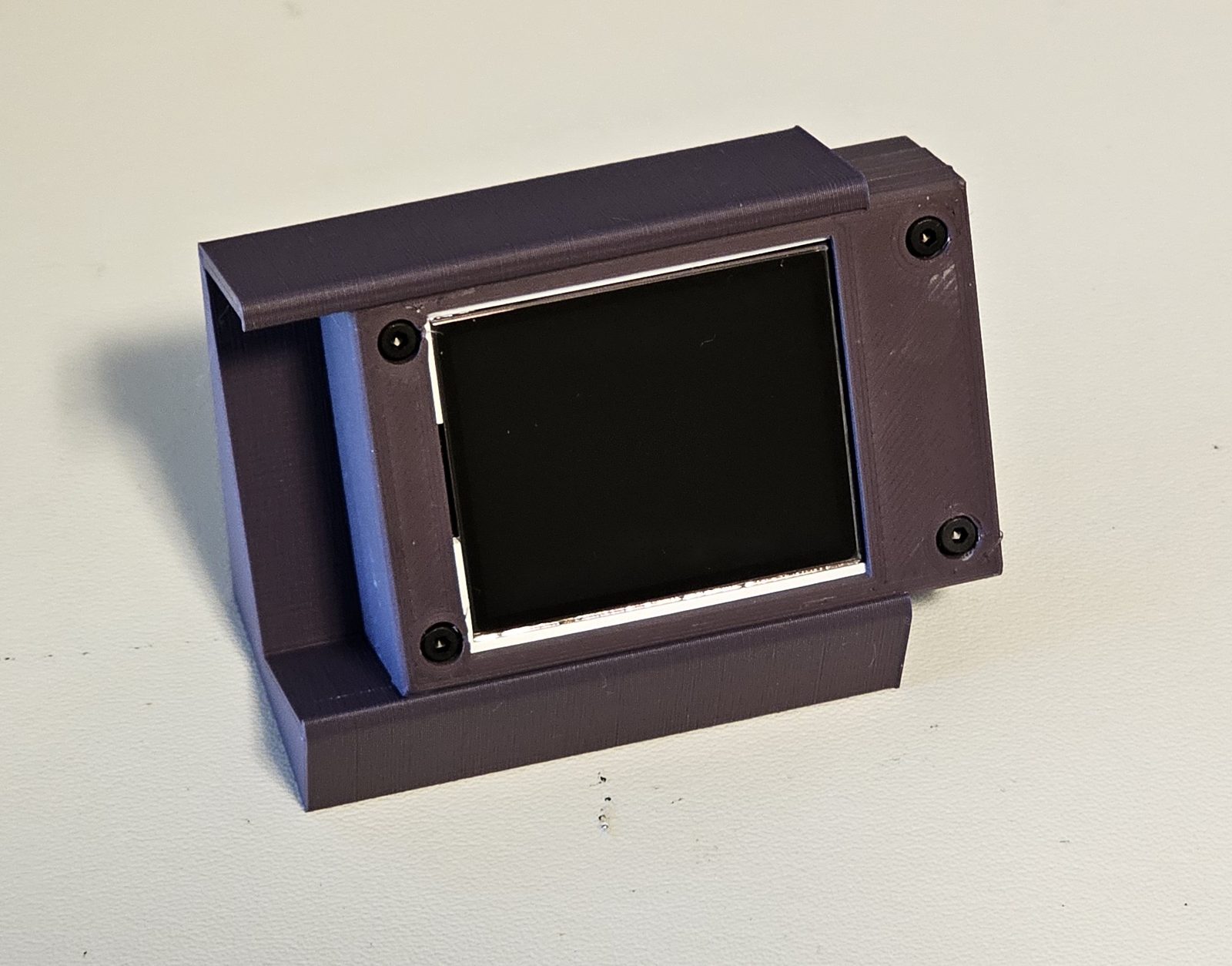 The enclosure seated in its angled 3D-printed stand, display off.